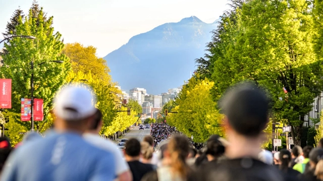 Corredores en una avenida arbolada de Vancouver con montañas al fondo